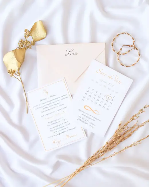 Wedding stationery and rings arranged on ivory fabric